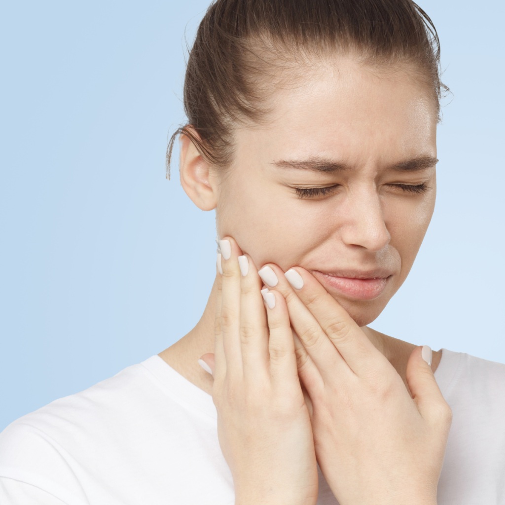 Young woman experiencing jaw pain, highlighting oral surgery services at Oral Surgery Associates in Grand Rapids and Grandville, Michigan.