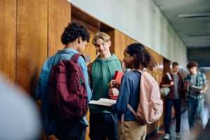 Teen students with backpacks talking in a school hallway